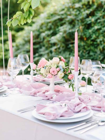 Wedding table in soft pink colours with candles, slatted runner and floral decoration on a tray.