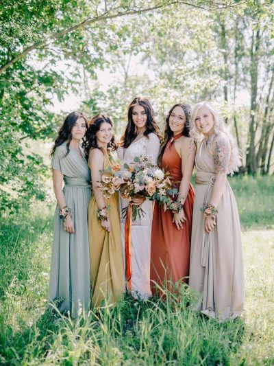 Bride with wedding bouquet and bridesmaids with floral bracelets in boho style