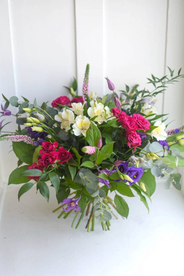Rich bouquet of red, white and purple flowers and assorted greenery.