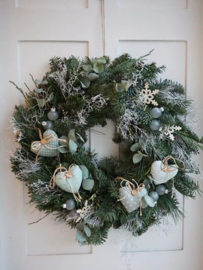 Christmas wreath to hang from evergreen fir twigs and white statice, decorated with fabric hearts, small glass balls and white wooden stars