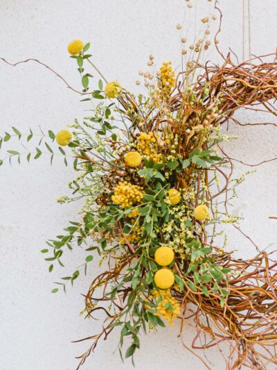 Spring wreath to hang weaved from Twisted willow with green eucalyptus and yellow dried mimosa, craspedia, statice and dried flax.