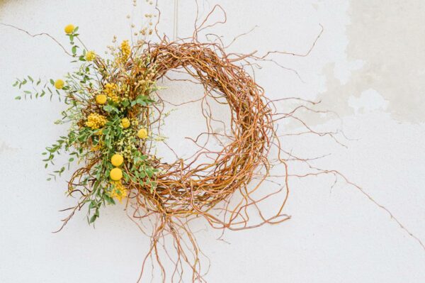 Jarní věnec umotaný z živé kroucené vrby, ozdobený sušenými žlutými květinami, sušeným lnem a zelení.