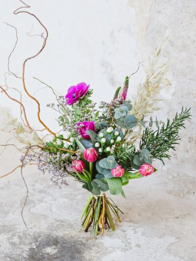 Bouquet made of pink tulips, anemone, veronica, limonium, rosemary, eucalyptus, decorated with twisted willow and dried oats.