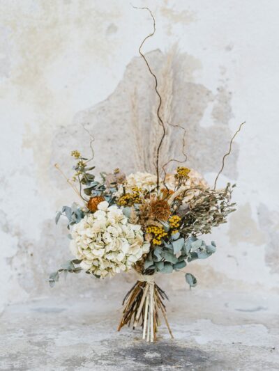 A large dried flower bouquet made of hydrangea, tansy, amaranth, eucalyptus, grasses, poppies and twisted willow twigs