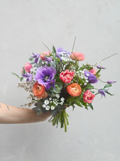 A colourful spring bouquet of ranunculus, tulips, anemones, clematis, garlic, genista and eucalyptus.