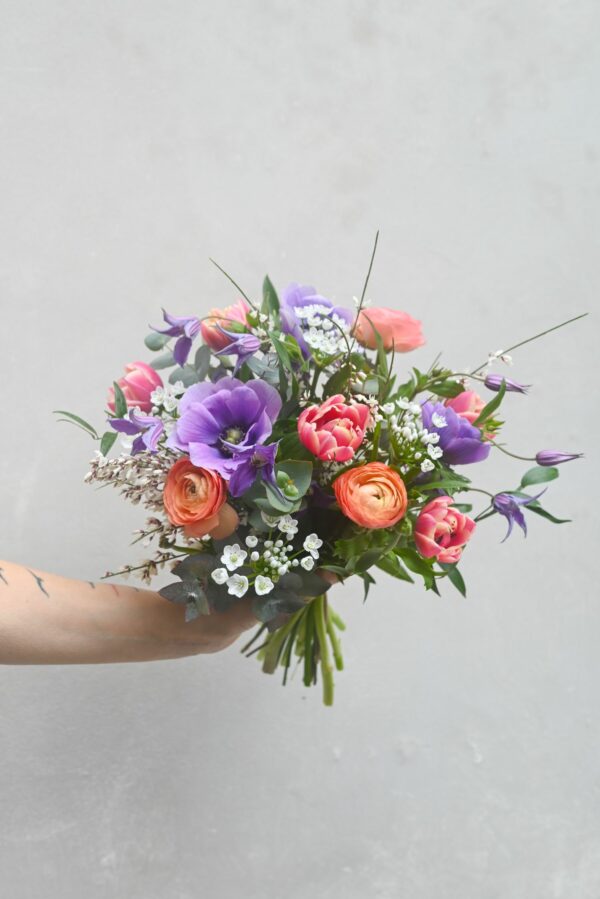 A colourful spring bouquet of ranunculus, tulips, anemones, clematis, garlic, genista and eucalyptus.