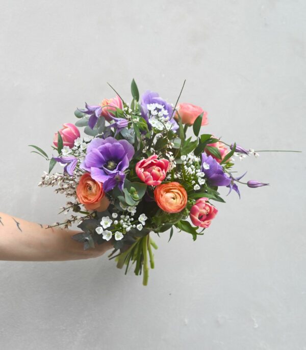 A colourful spring bouquet of tulips, anemones, ranunculus, clematis, garlic, genista and eucalyptus.